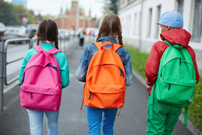 3 kids on way to school wearing colorful backpacks