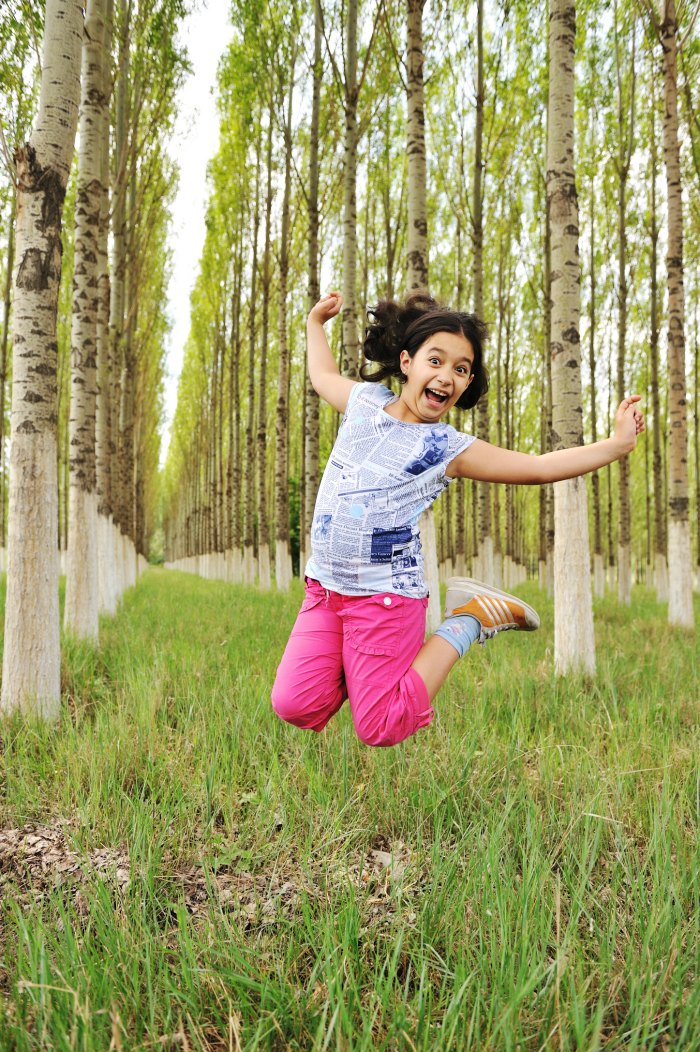 girl jumping in wooded area