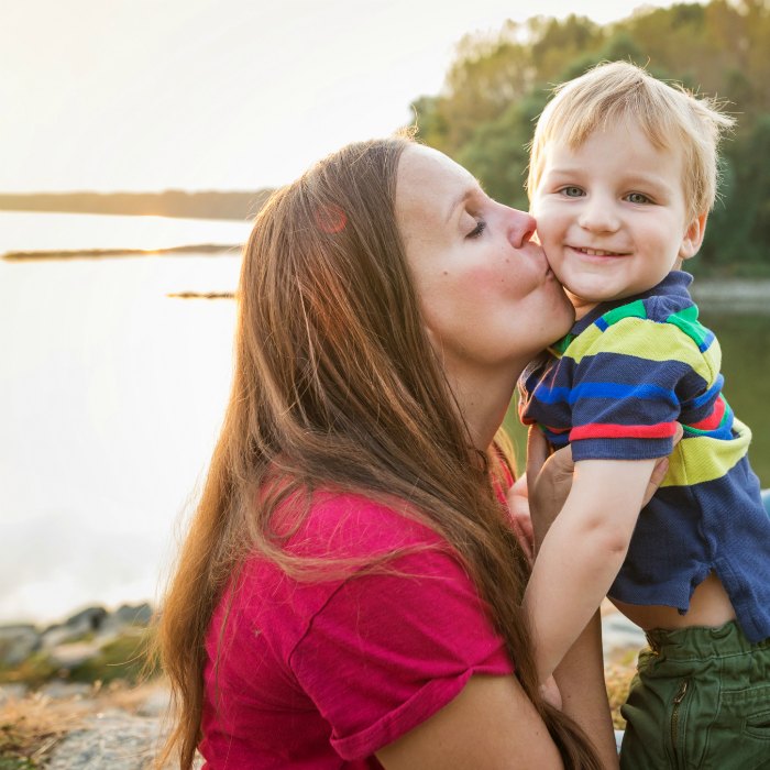 mom kissing son with lake in background