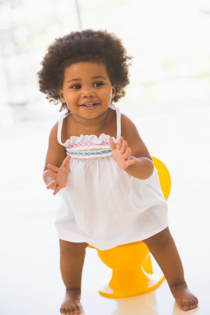 little black girl standing in front of yellow potty
