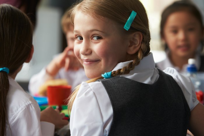 young girl in braids wearing school uniform smiling over her shoulder