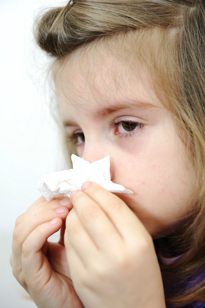 girl with allergies blowing nose