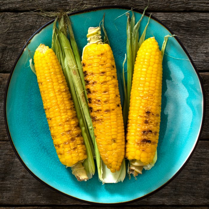 grilled corn with husks on blue plate