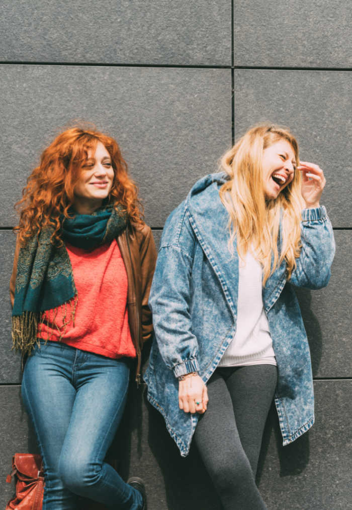 Two young women strolling outdoor in the city, blonde and redhead having fun - friendship, relaxing, having fun concept