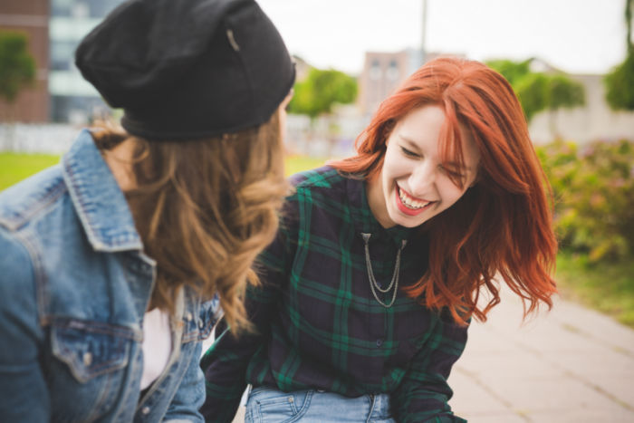 Half length of two young handsome caucasian women friends chatting, focus on the redhead laughing - smiling, friendship, having fun concept
