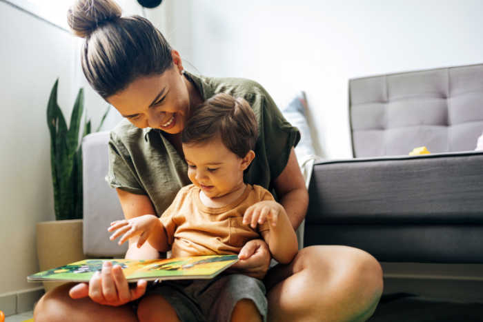 mother reading interactive board book with young toddler