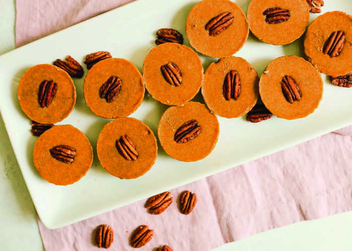 no bake pumpkin pie bites with pecan in centers on light green tray