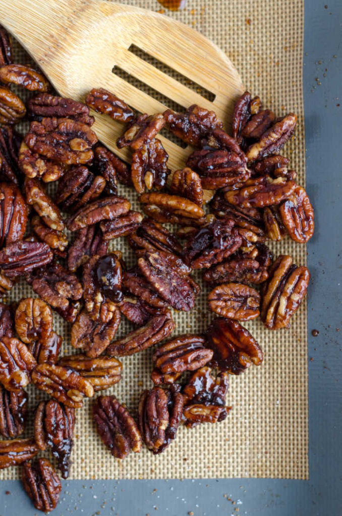 pecans in process on baking mat with wooden spoon