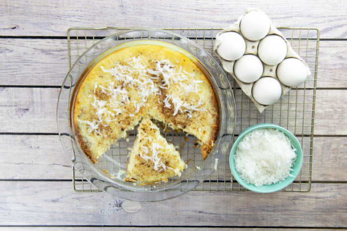 Overview look of coconut custard pie on a cooling rack - with ingredient examples of eggs and coconut