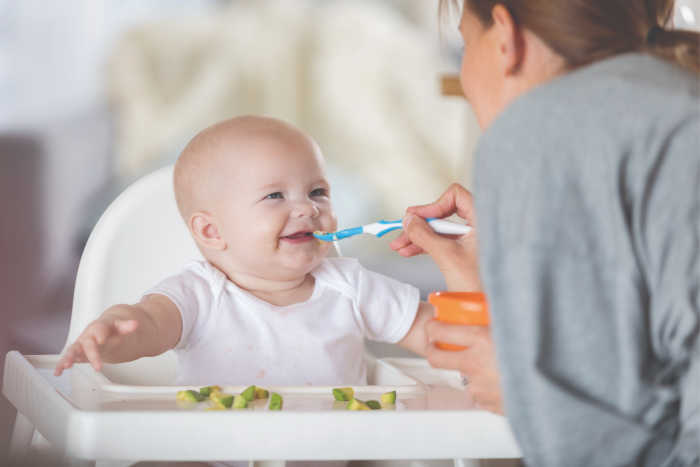 baby smiling arms waving being spoon fed by mom