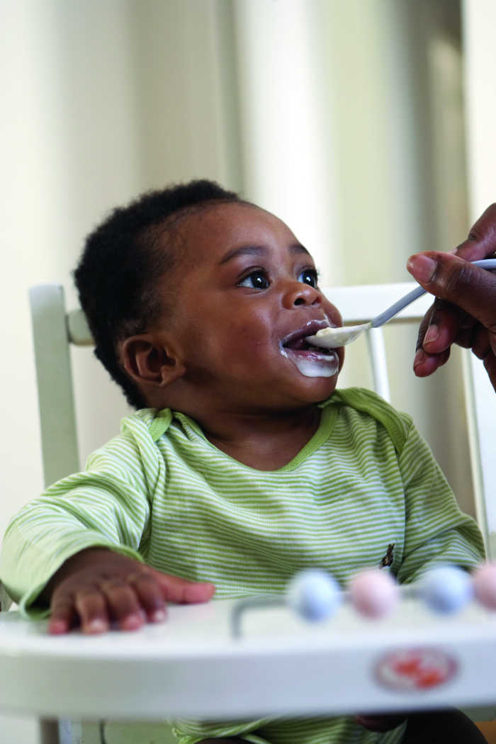 baby smiling being spoon fed first solid foods