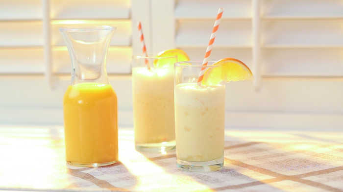 carafe of orange juice with two glasses of orange cream smoothie