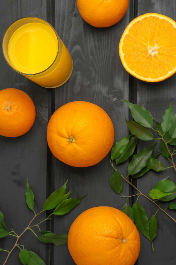 orange juice with oranges and leaves on wood background