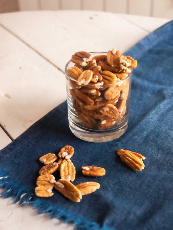 pecans in a clear glass on a blue cloth