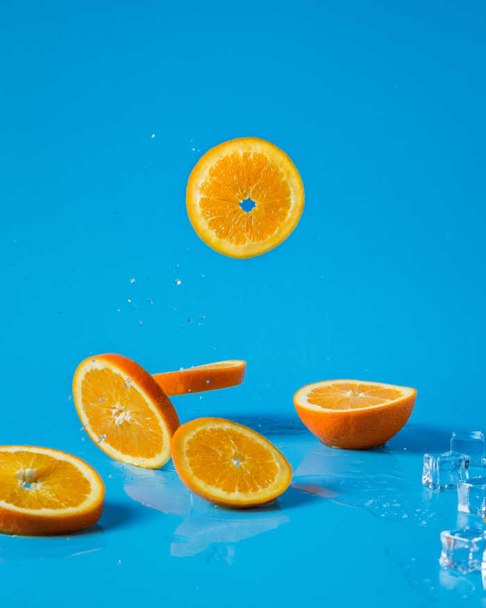slices of oranges falling down with bright blue background