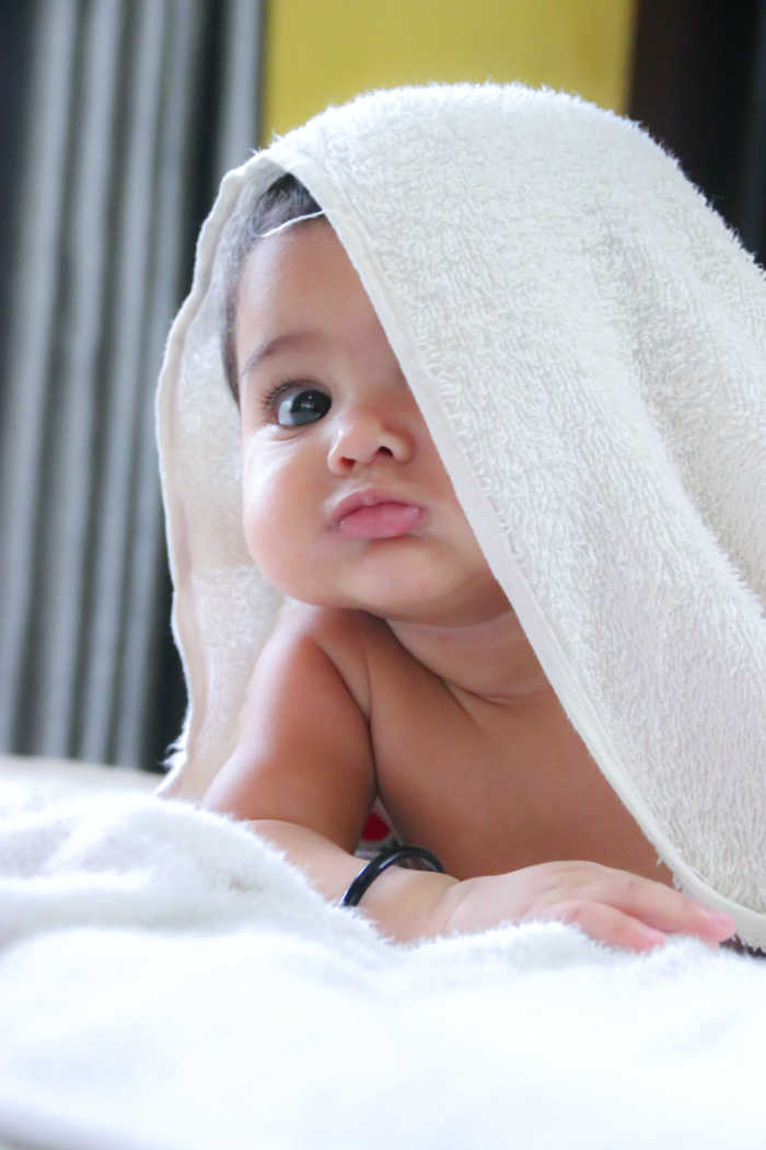 cute baby girl peeking out from under white towel