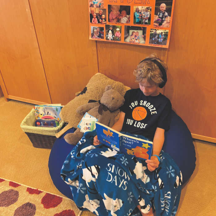 Quiet safe space for a child to reset, including comfy seating, headphones, plush stuffed animals and books.