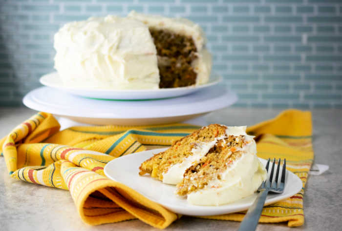 Piece of easy carrot cake recipe on a plate with fork and yellow napkin