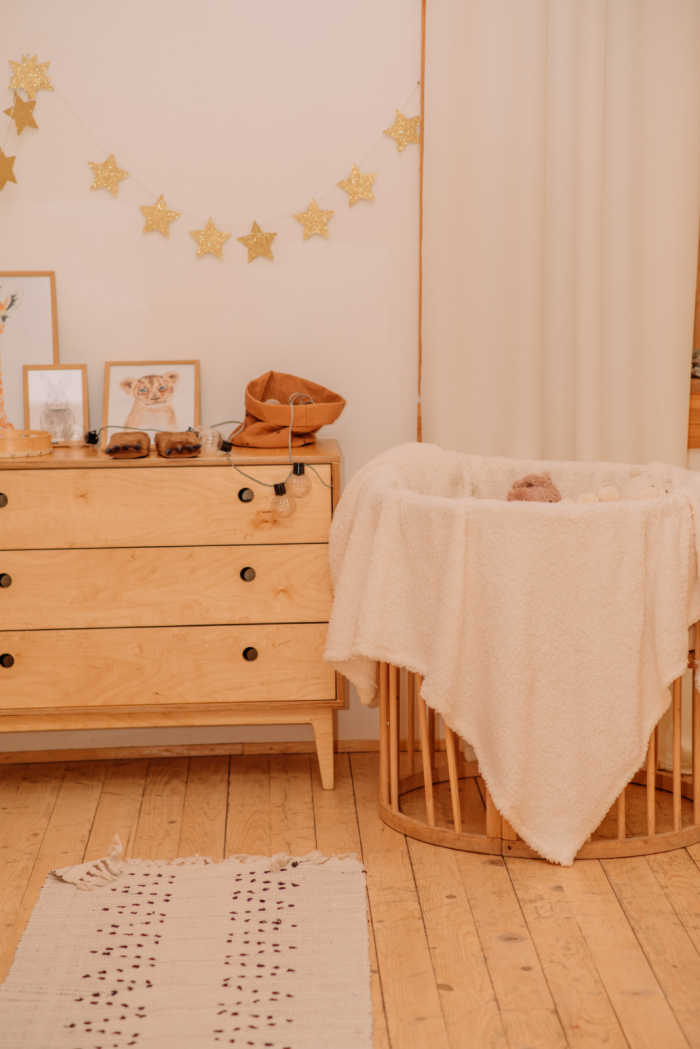 maple wood crib with cream blanket and side table