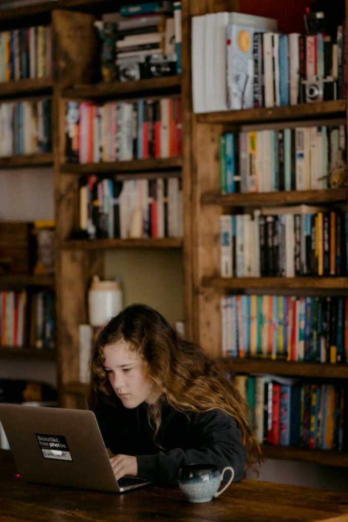 girl on computer in front of book shelves