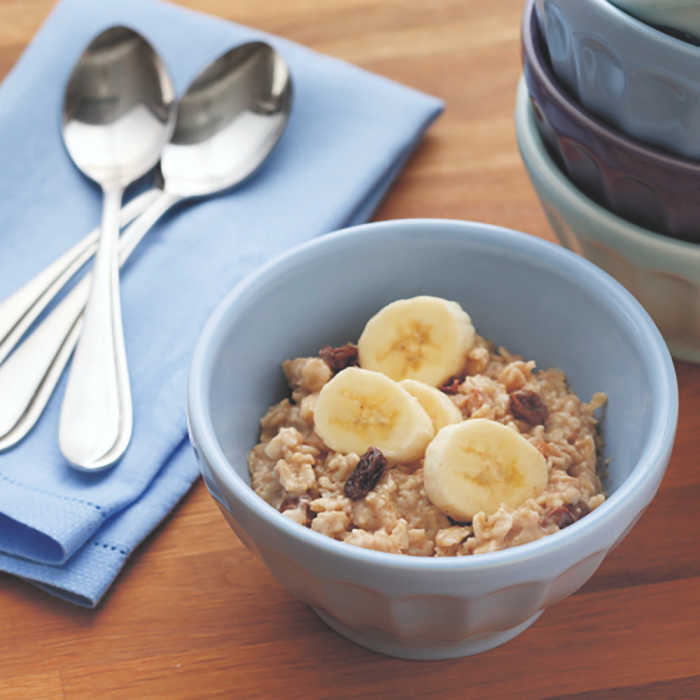 peanut butter oatmeal with bananas in a blue bowl with spoons