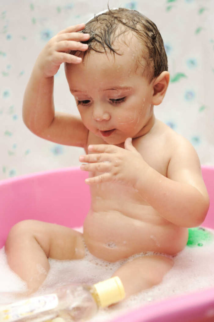 toddler in bath tub with shampoo bottle - washing toddlers hair