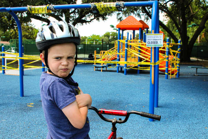 angry boy on bike with arms crossed because playground is closed