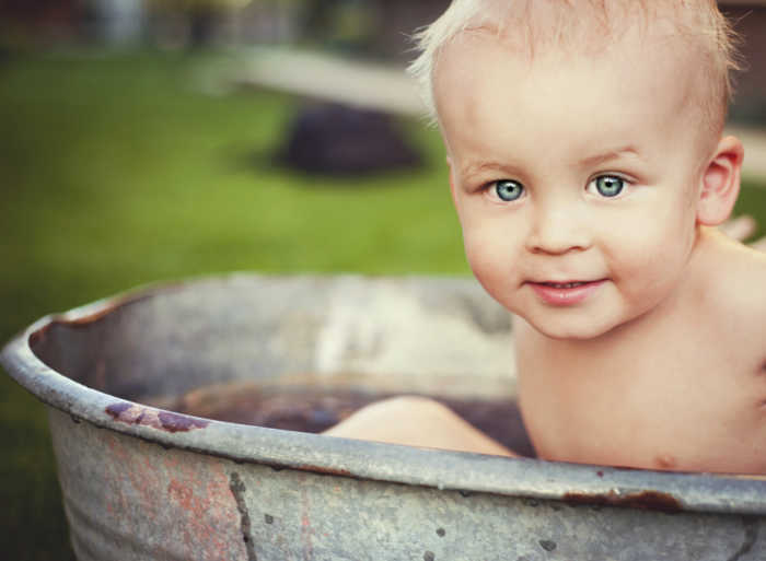 toddler in rustic tub outside