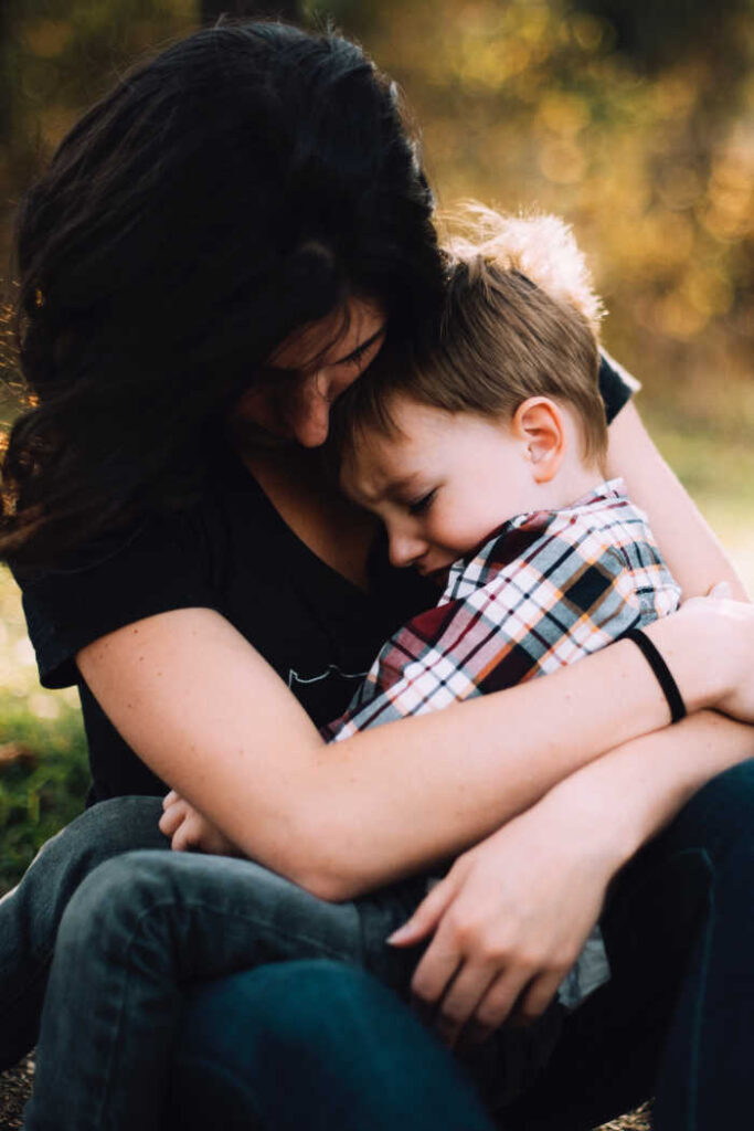 upset young boy in arms of mom being comforted