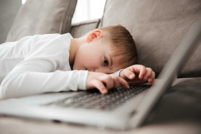 boy laying on couch looking at computer