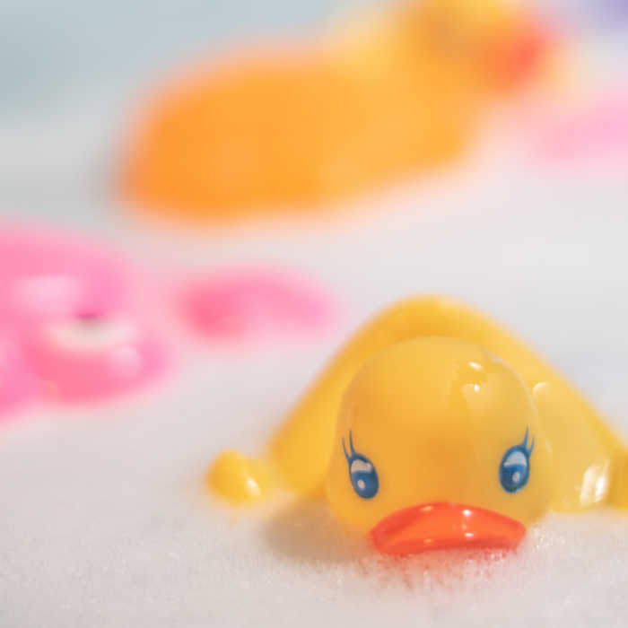 rubber duckie floating on soap suds in bath tub