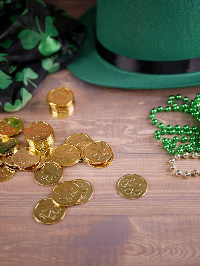 st patrick's day green hat, green beads and gold coins on wood surface