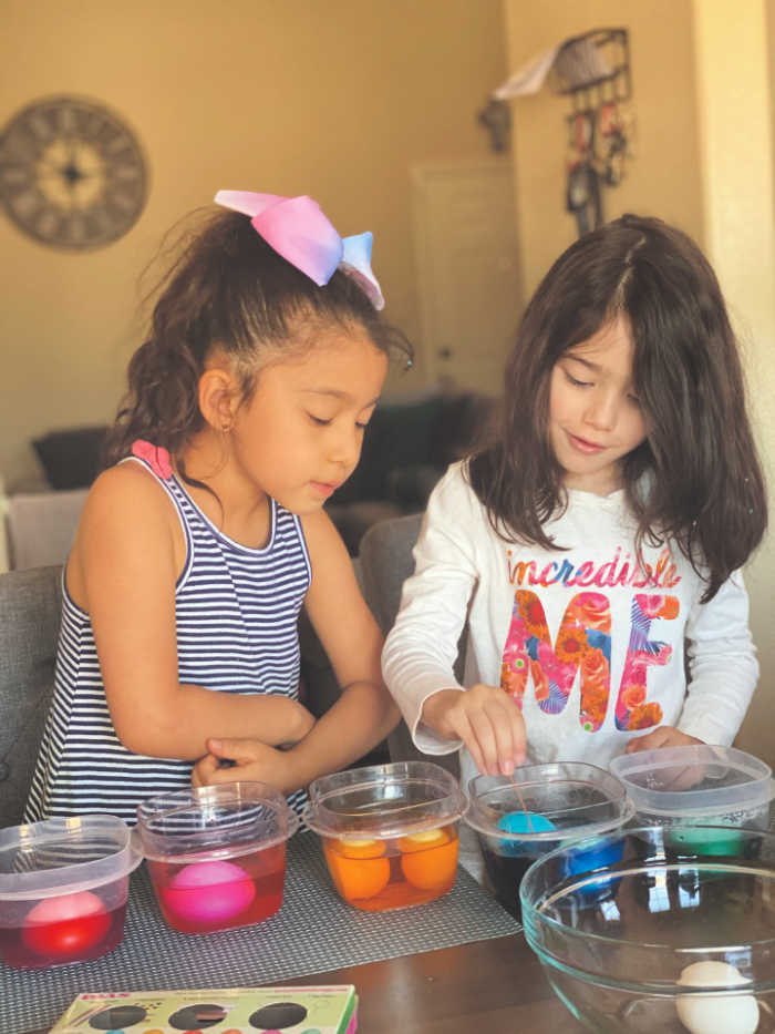 Girls dyeing eggs in plastic containers