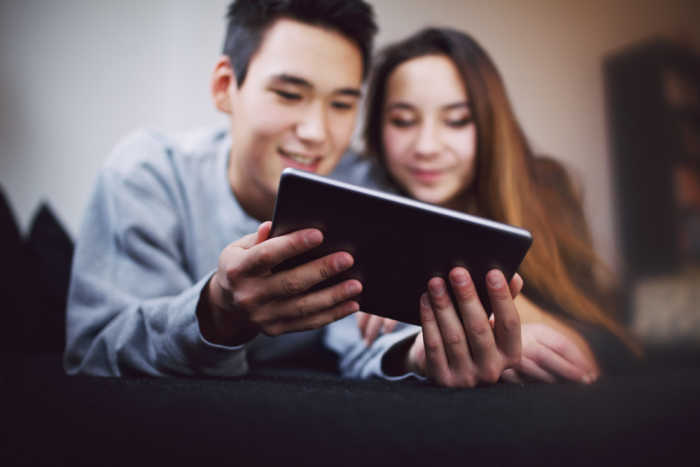 young teen couple looking at computer tablet