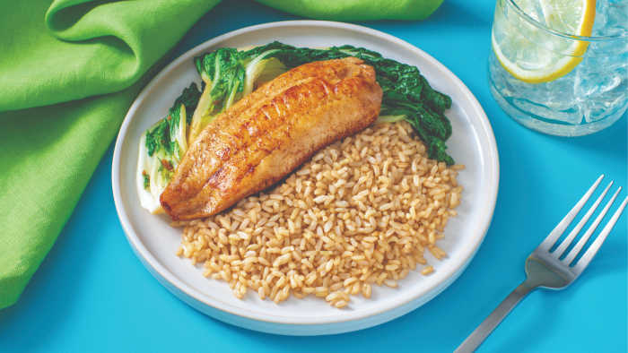 white fish, bok choy and brown rice on a white plate