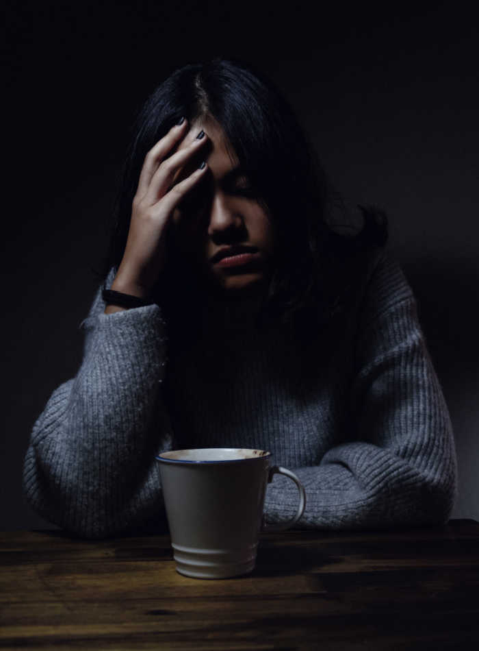 woman with headache and period pain sitting with coffee cup