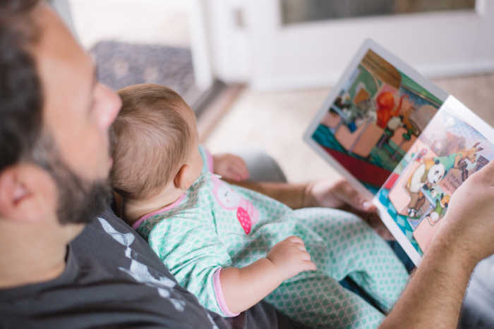 dad reading baby board book to infant