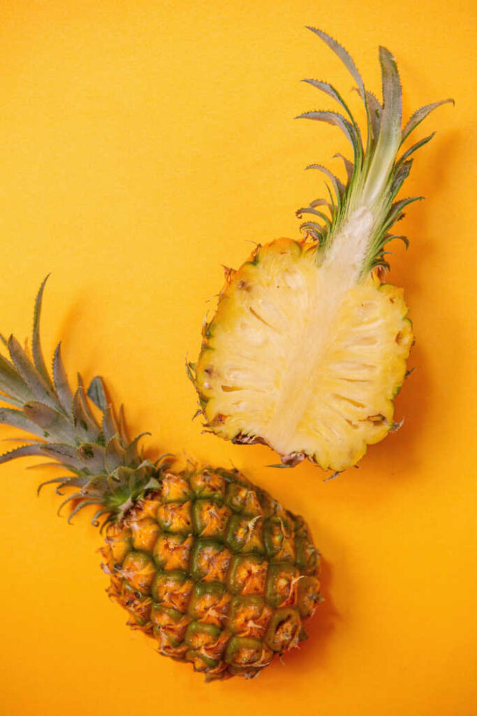 pineapple cut in half on yellow background