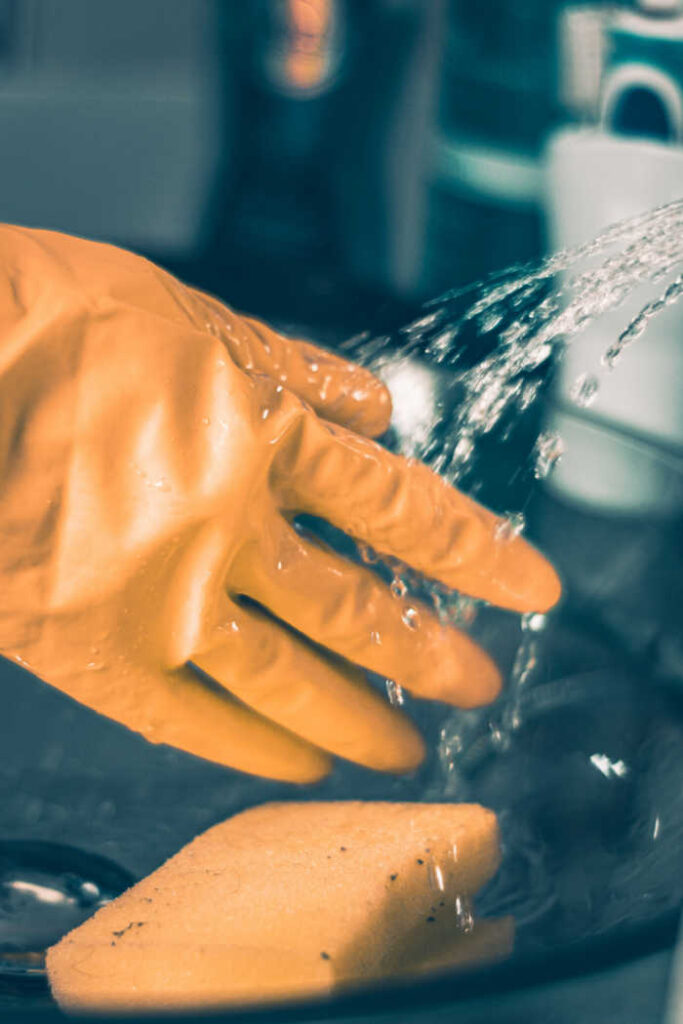 yellow gloves rinsing off sponge with water