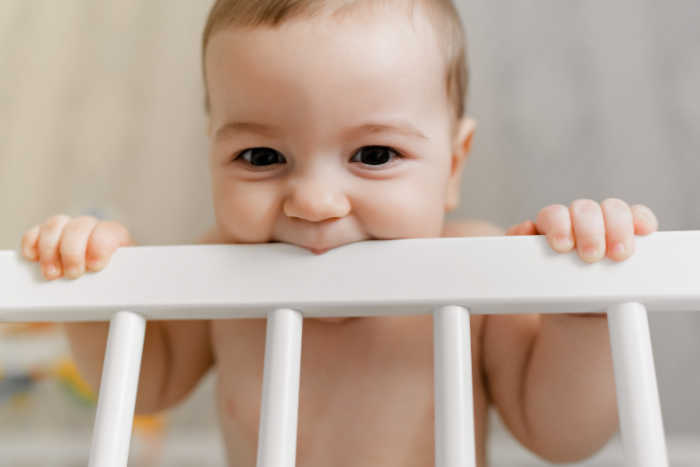 baby chewing on crib