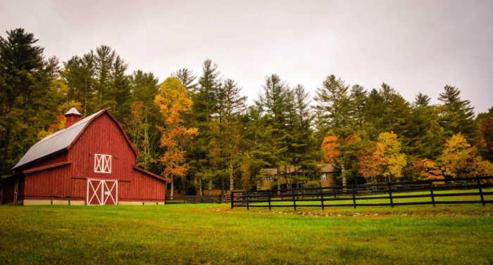red barn on farm surrounded by fall leaves