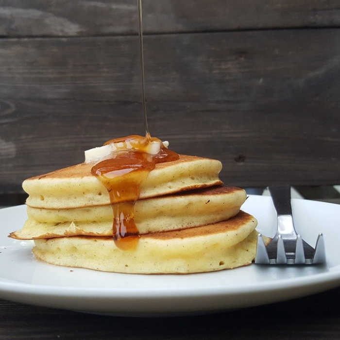 pancakes with syrup and fork on white plate