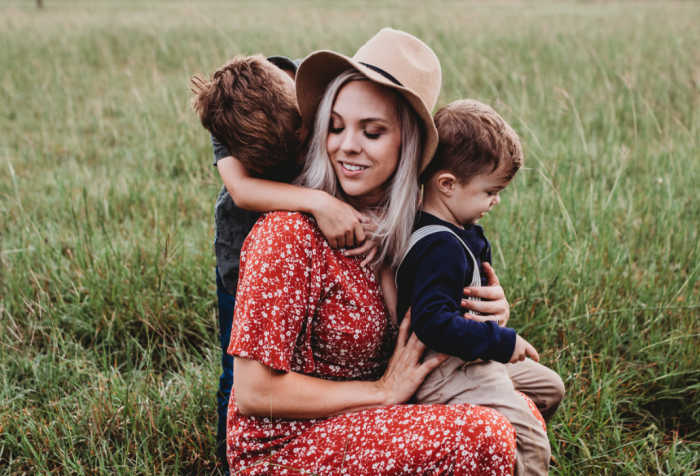 mother with boys sitting in grass field