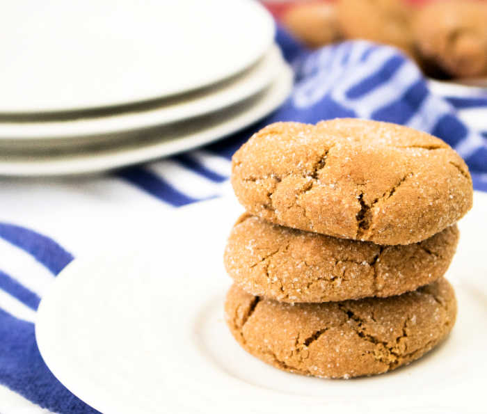 Chewy gingersnaps on white plate with blue stripe dish towel in background