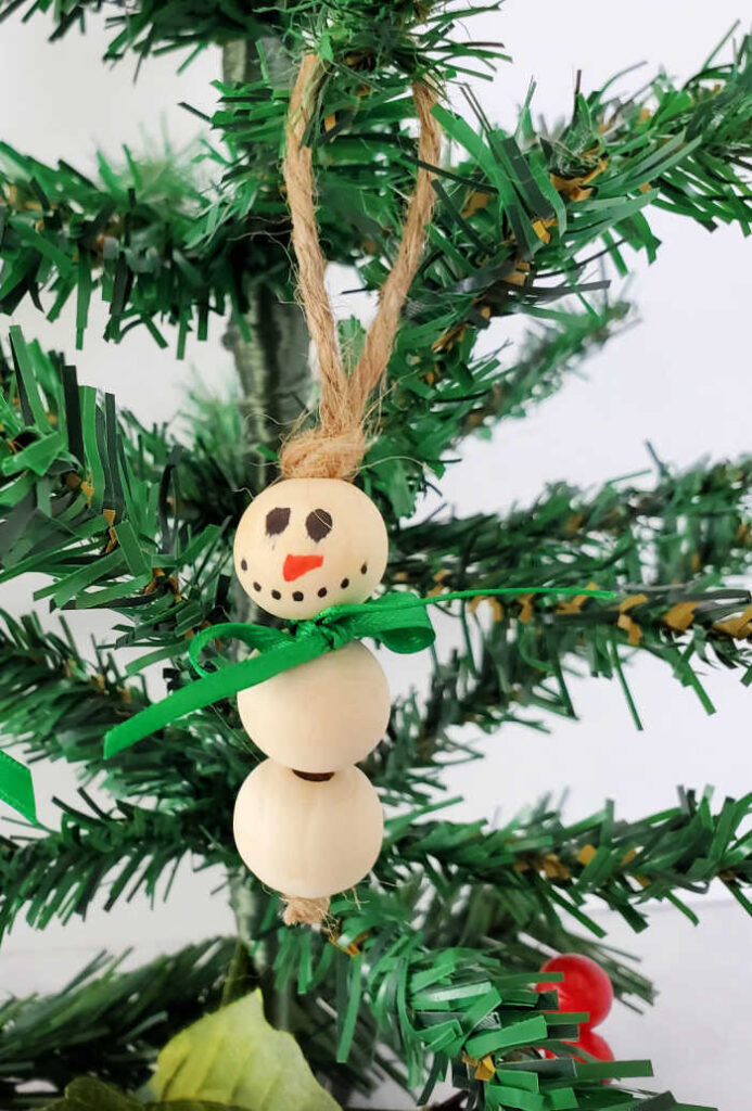 A simple yet adorable craft project to make using wooden beads and twine, this snowman ornament craft is a perfect way to decorate your tree! A perfect kid craft for the season or homemade ornaments for your Christmas Tree.