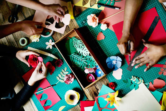 multiple folks cutting paper creating crafts- the benefits of crafting including teamwork