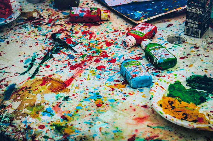 paint bottles and paint splattered everywhere on white table