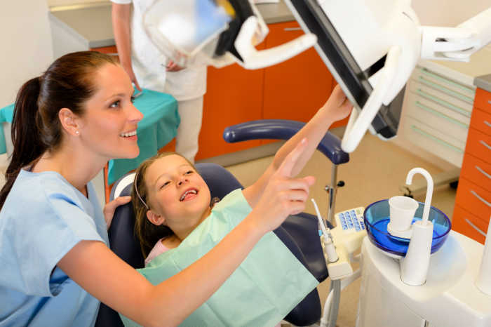Smiling dentist and child pointing at the screen office