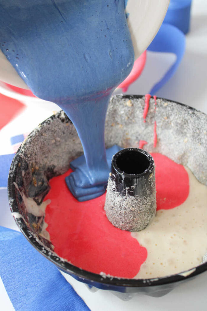 white red and blue bundt cake batter being poured into bundt pan