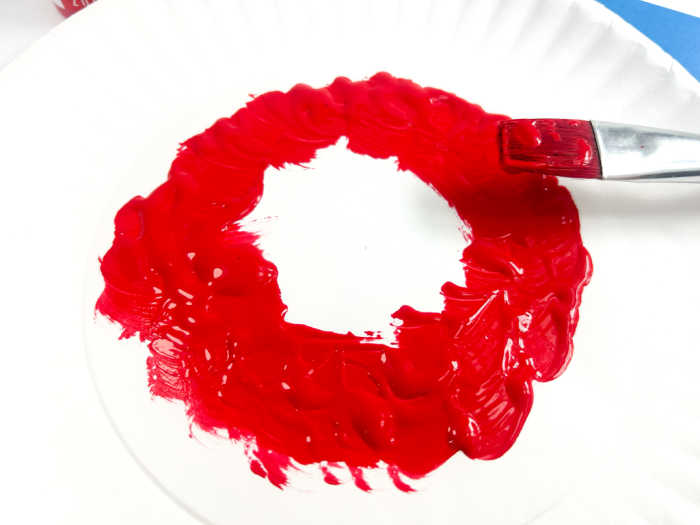 Pour craft paint on a paper plate in a circle. Use a paintbrush to evenly distribute the paint. 